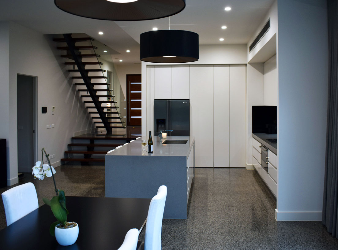 Luxury kitchen in a Heidelberg custom home featuring glass, stone, and polished concrete surfaces with high-end joinery.